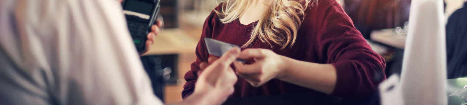 Cropped image of woman handing debit card to store employee